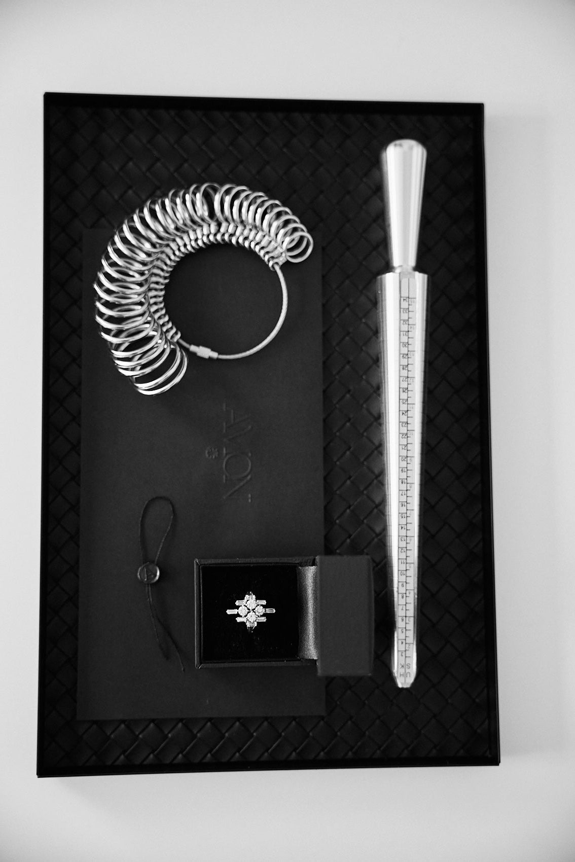 Jewelry set with ring sizer, coil, and diamond ring on a black mat